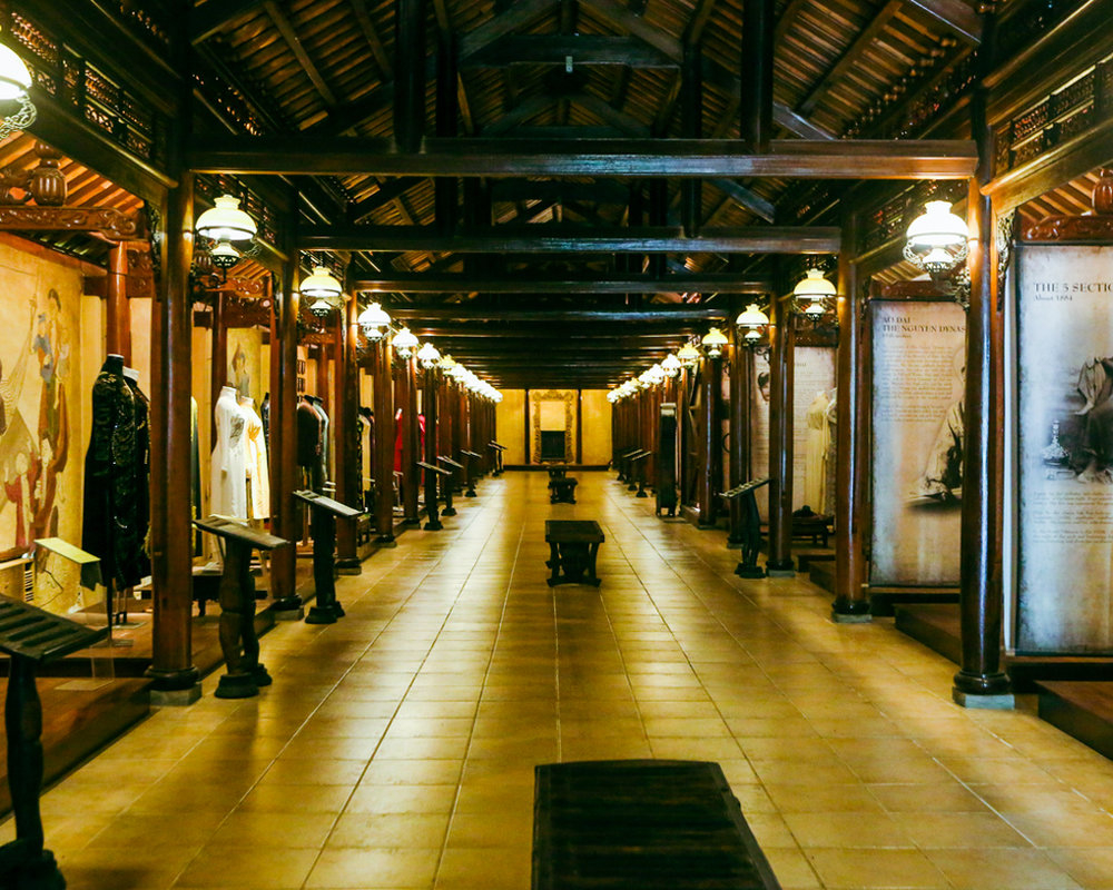 The warm, dim lighting casts a nostalgic glow, enhancing the elegance of the traditional ao dai on display